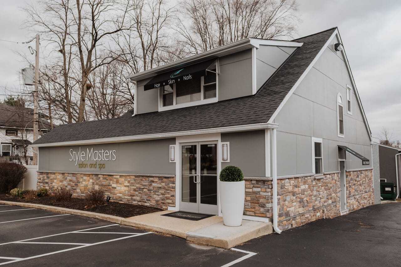 Salon and spa building with gray siding and stone accents, featuring large glass entrance doors.