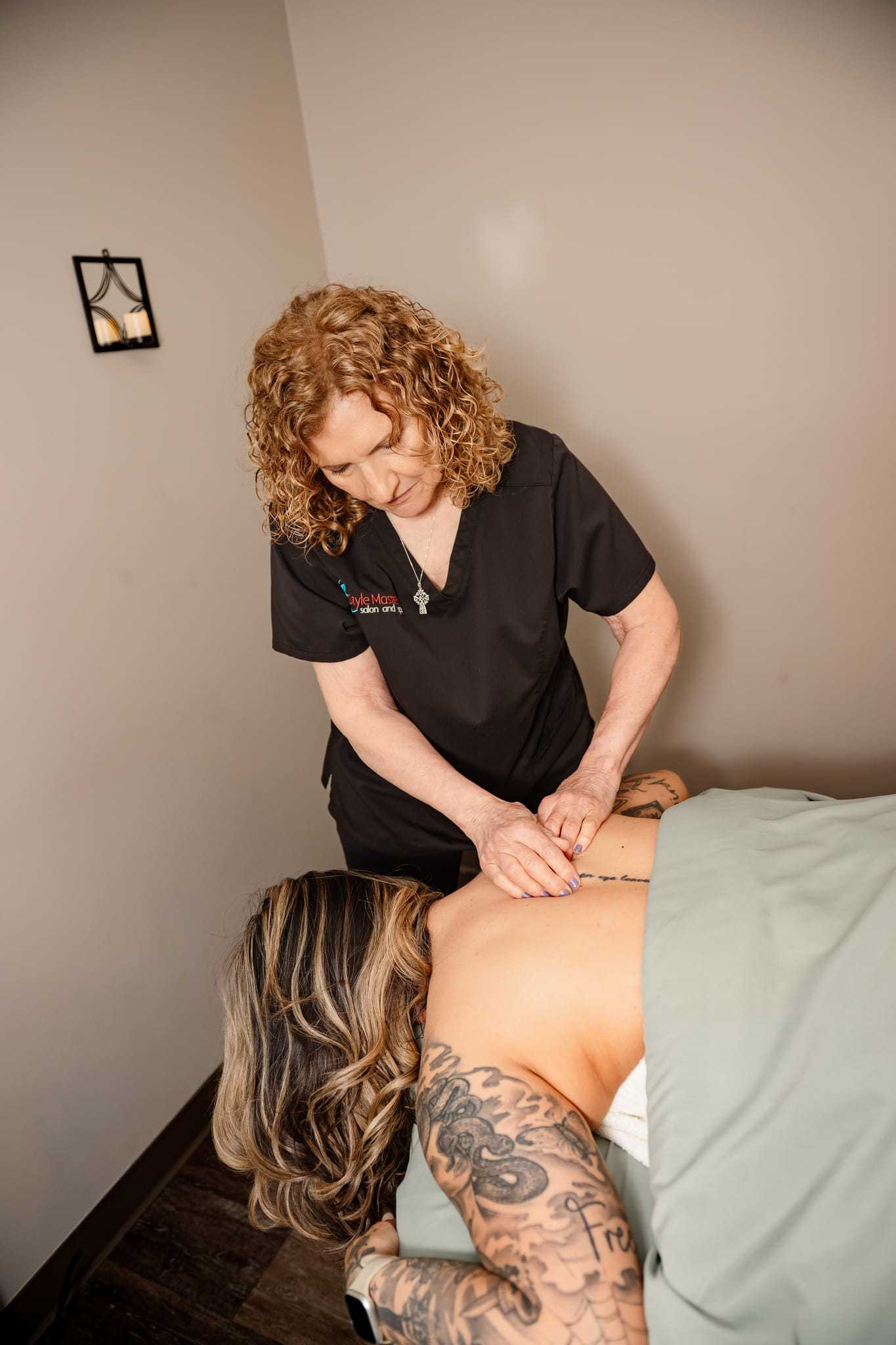 Massage therapist giving a back massage in a calm spa room.