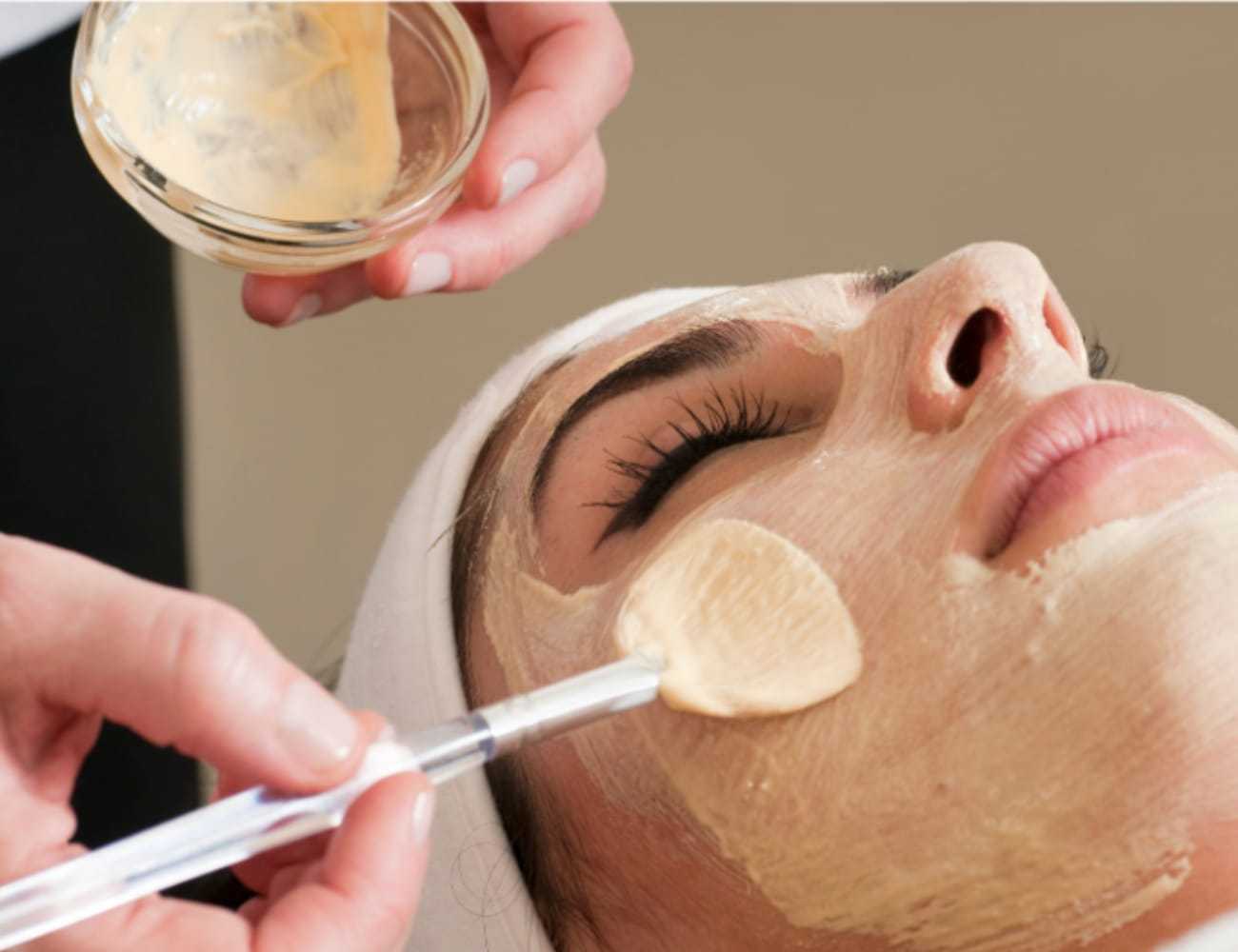 Facial treatment being applied with a brush to a relaxed person's face.