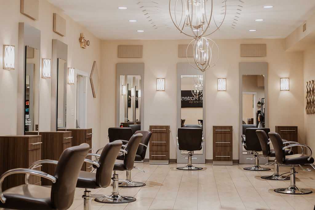 Modern salon interior with multiple styling chairs, mirrors, and elegant lighting fixtures.